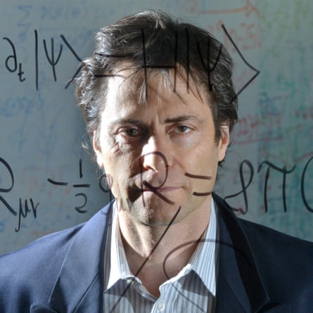 Max Tegmark stands behind a clear board with the Schrödinger equation for quantum mechanics and Einstein's general theory of relativity written on it.