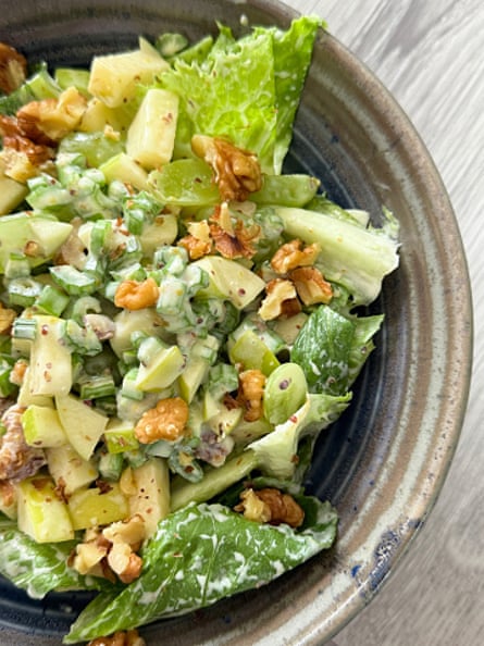 Stock photo showing close-up, elevated view of a healthy eating image of a salad bowl containing a Waldorf salad made with iceberg lettuce, celery, fruit and nuts topped with yoghurt based sauce.