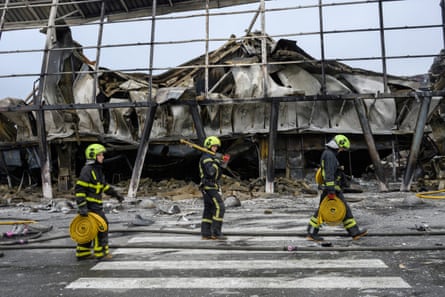 Emergency workers walk by a damaged shopping centre in Kyiv, Ukraine.