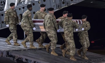 Soldiers in uniform carry a coffin on a ramp from a plane