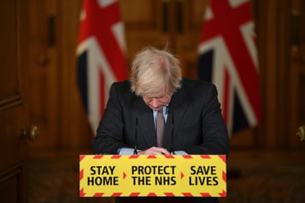 Boris Johnson Down Street, head bowed, union flag in the background, at a podium with sign ‘Stay Home, Protect the NHS, Save Lives’