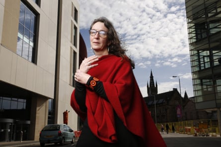 Prof Alison Phipps stands outside a Glasgow university building wrapped in a red shawl.