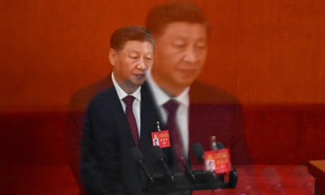 Double exposure photo showing a larger image of Xi superimposed on a smaller one. he is shown from the waist up standing against a red background