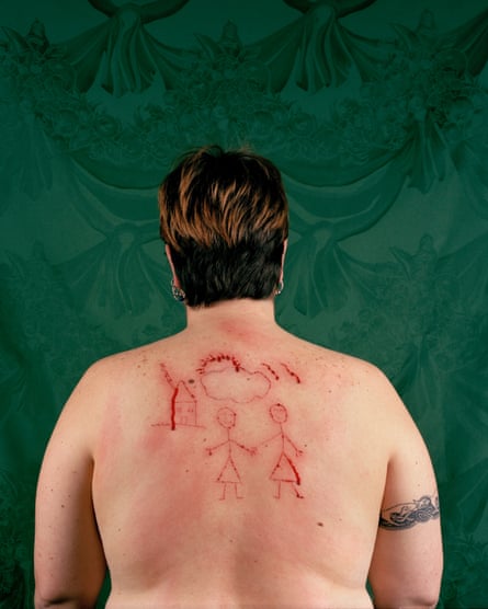Catherine Opie with her back to the camera, topless, with bloody etchings of a drawing on her back