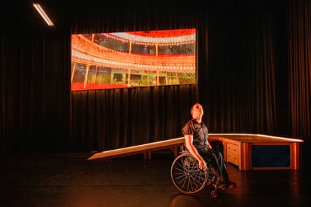 A dancer using a wheelchair gazes upwards.