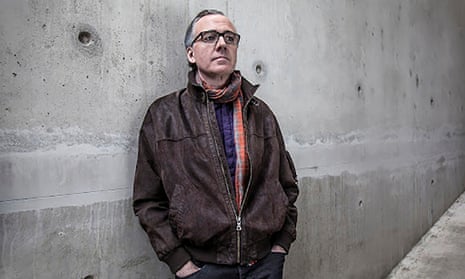 Middle-aged white man with gray hair and glasses leaning against cement wall looking artistic.