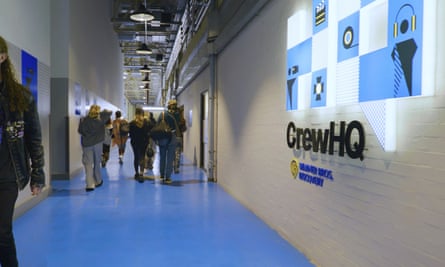 People in a studio corridor that has a CrewGQ logo on the wall. 