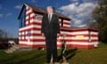 woman outside a house painted like the american flag holding hands with a huge Trump cut out
