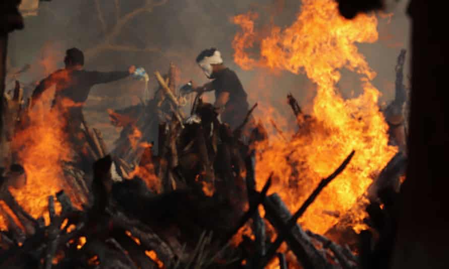 Relatives stand next to burning funeral pyres of those who died of coronavirus, at Ghazipur cremation ground in New Delhi.