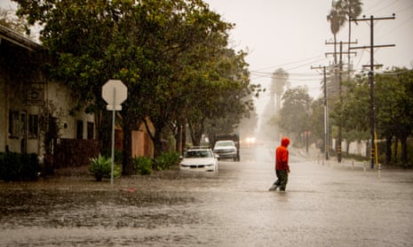 A man crosses a flooded street in Santa Barbara, California, on 4 February 2024. 