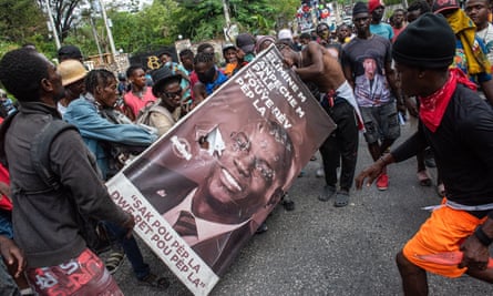 Protesters damage a poster with the image of assassinated president Jovenel Moise during a demonstration against authorities’ inaction against criminal gangs, in Port-au-Prince, Haiti, 30 March 2022.