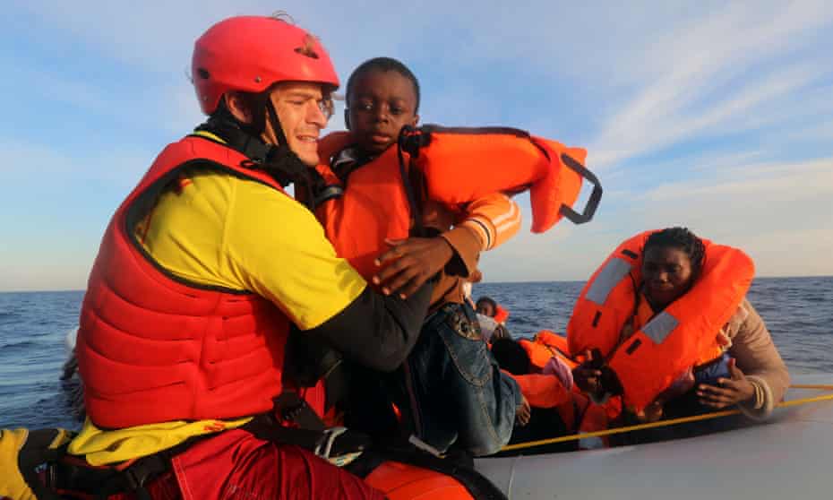 Daniel Calvelo, 26, carries a child into a boat during a rescue operation off the Libyan coast by Spanish NGO Proactiva Open Arms