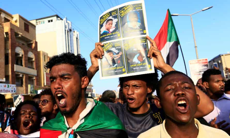 Sudanese protesters hold posters and flags in Khartoum