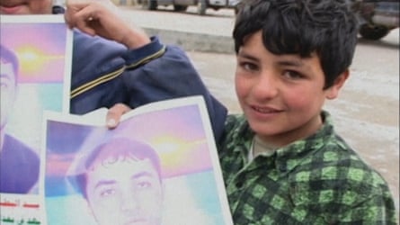 A boy holds up a picture of a man in a still from Eliane Raheb’s Suicide, 2003.