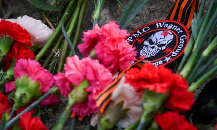 Flowers and a patch with the Wagner logo, laid at the memorial site