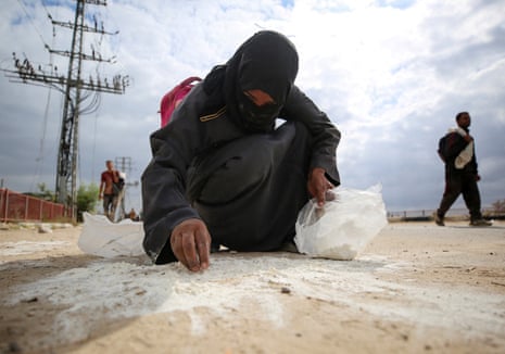 A woman collects flour from the ground in the central Gaza Strip on 1 August 2025.