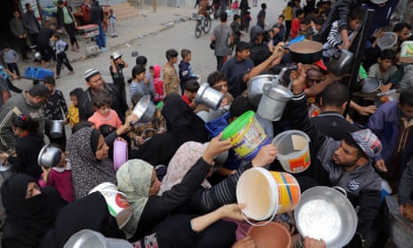 People wait for food relief in the southern Gaza Strip city of Rafah