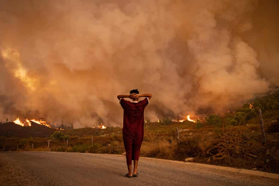 A woman watches wildfires tearing through a forest in the region of Chefchaouen in northern Morocco in August 2021