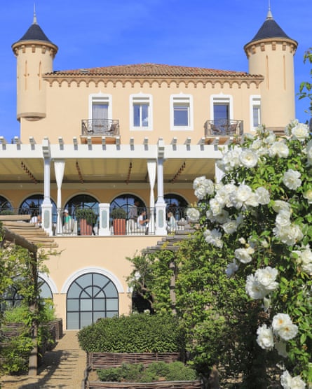 Image of the front of the large cream coloured chateau with lots of hanging flowers and plants across the veranda