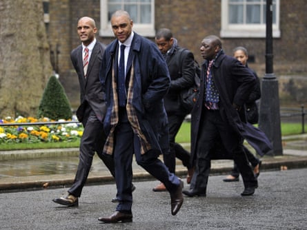 Five men of colour walking past a brown brick building