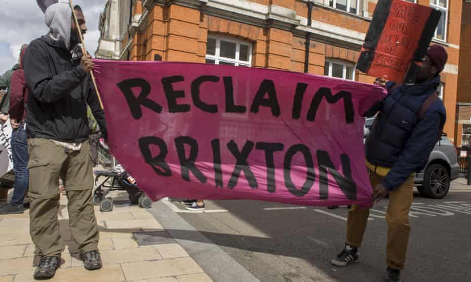 Two men hold a banner with the words Reclaim Brixton