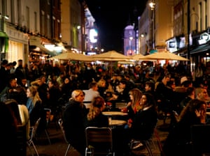 Customers sit at tables outside bars and restaurants in Soho on the eve of a second coronavirus lockdown to combat soaring infections.