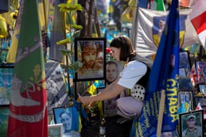 A woman crouches at a makeshift memorial site
