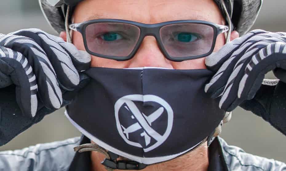 An Extinction Rebellion activist wearing mask with airliner with line through it