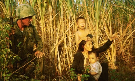 An image by Tim Page of a soldier from the Korean White Horse Division with a mother and children from a suspected Viet Cong family, near Bong Son, Vietnam, 1966.