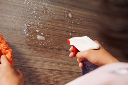 Closeup of woman hand cleaning the surface of a wood table with a cleaning cloth at home