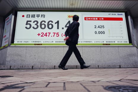 A person looks at an electronic stock board showing Japan’s Nikkei index at a securities firm in Tokyo