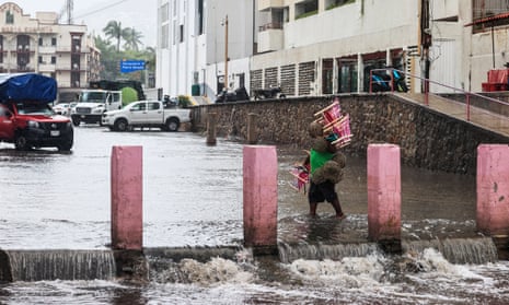 A person walks through a flooded street in Acapulco, Guerrero state, Mexico.