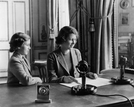 Princess Elizabeth and Princess Margaret sitting at a desk with old-fashioned microphones in front of them