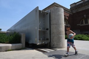 A boy with a ball walks through the open sliding steel flood gate
