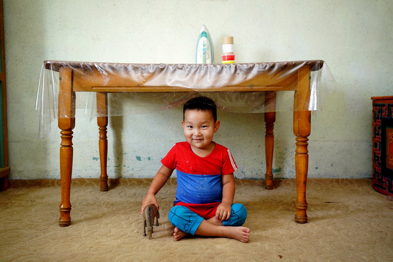 A boy plays with his toy horse at home, surrounded by traditional Mongolian items, in Khanbogd