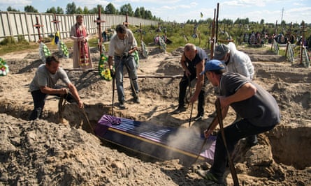 Volunteers lower into a grave a coffin with one of 15 unidentified people killed by Russian troops, in the town of Bucha, in Kyiv region, on 2 September.