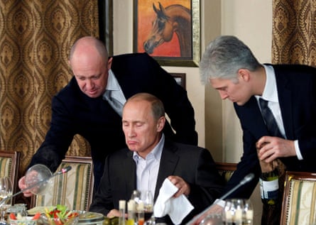 Prigozhin (left) assists Vladimir Putin during a dinner with foreign scholars and journalists outside Moscow in November 2011