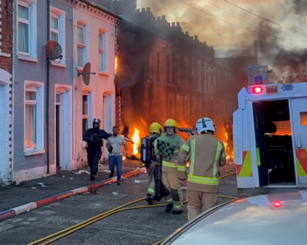 A man is guided to safety by a PSNI officer after being rescued from houses which caught fire in Lendrick Street in east Belfast