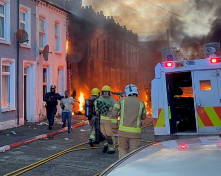 A man is in Belfast is guided to safety by after being rescued from houses on fire in Lendrick Street.