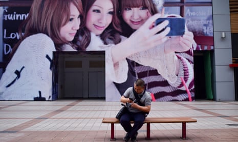 A man looks at his mobile phone in front of a huge poster along a business street in Beijing
