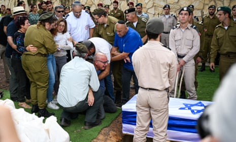 The father of Valentin (Eli) Ghnassia, 23, who was killed in a battle with Hamas militants at Kibbutz Be’eeri near the Israeli border with the Gaza Strip cries next to the casket before it is lowered during his funeral at Mount Herzl Military Cemetery in Jerusalem.