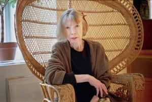 Joan Didion wears black and neutral knitwear while seated in a winged wicker chair in her Upper East Side apartment in New York City in 2003.