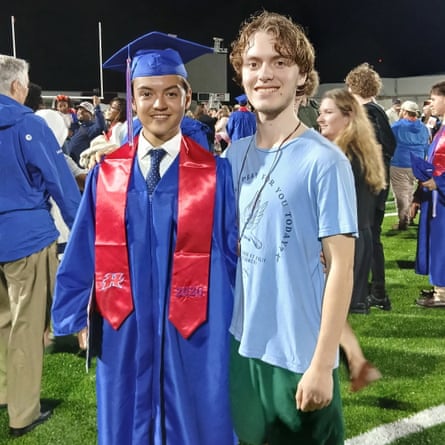 Two teenagers connected a shot field, pinch 1 successful graduation regalia and nan different successful a T-shirt.