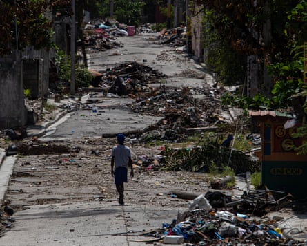 Debris-strewn street in appalling state, solitary man walks along it