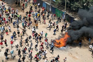 Protesters run towards riot police officers during a mass rally called by the opposition leader Raila Odinga over the high cost of living in Kibera, Kenya