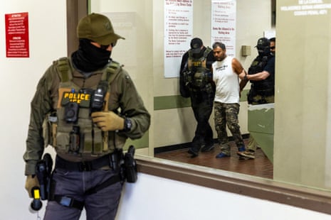 Masked men frogmarch a detained a person down a corridor
