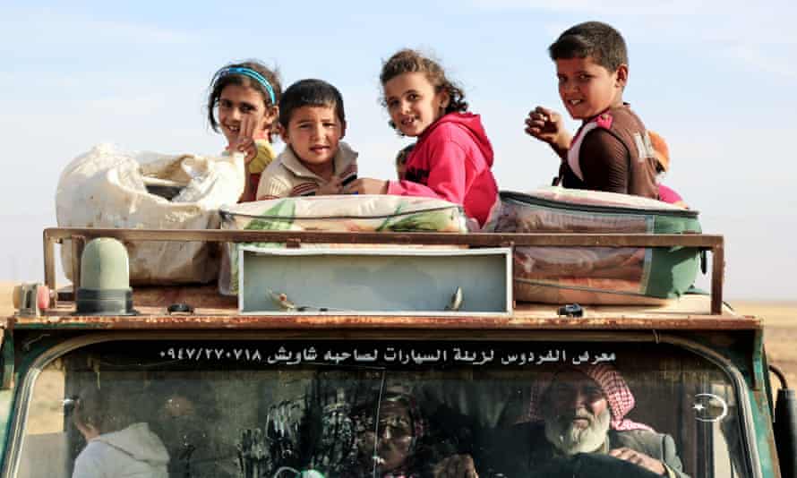 Syrian children smile from a pickup truck, as they come to safety after fleeing areas controlled by the jihadist group Islamic State