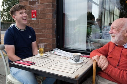 Two men sitting opposite each other at a table outside a restaurant