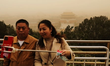 Visitors pose for a shot with the Forbidden City at Jingshan Park in the background.