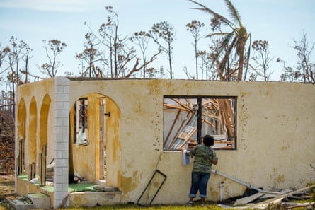 A woman looks through a broken window into a destroyed house in the High Rock community in the eastern side of Grand Bahama island.
